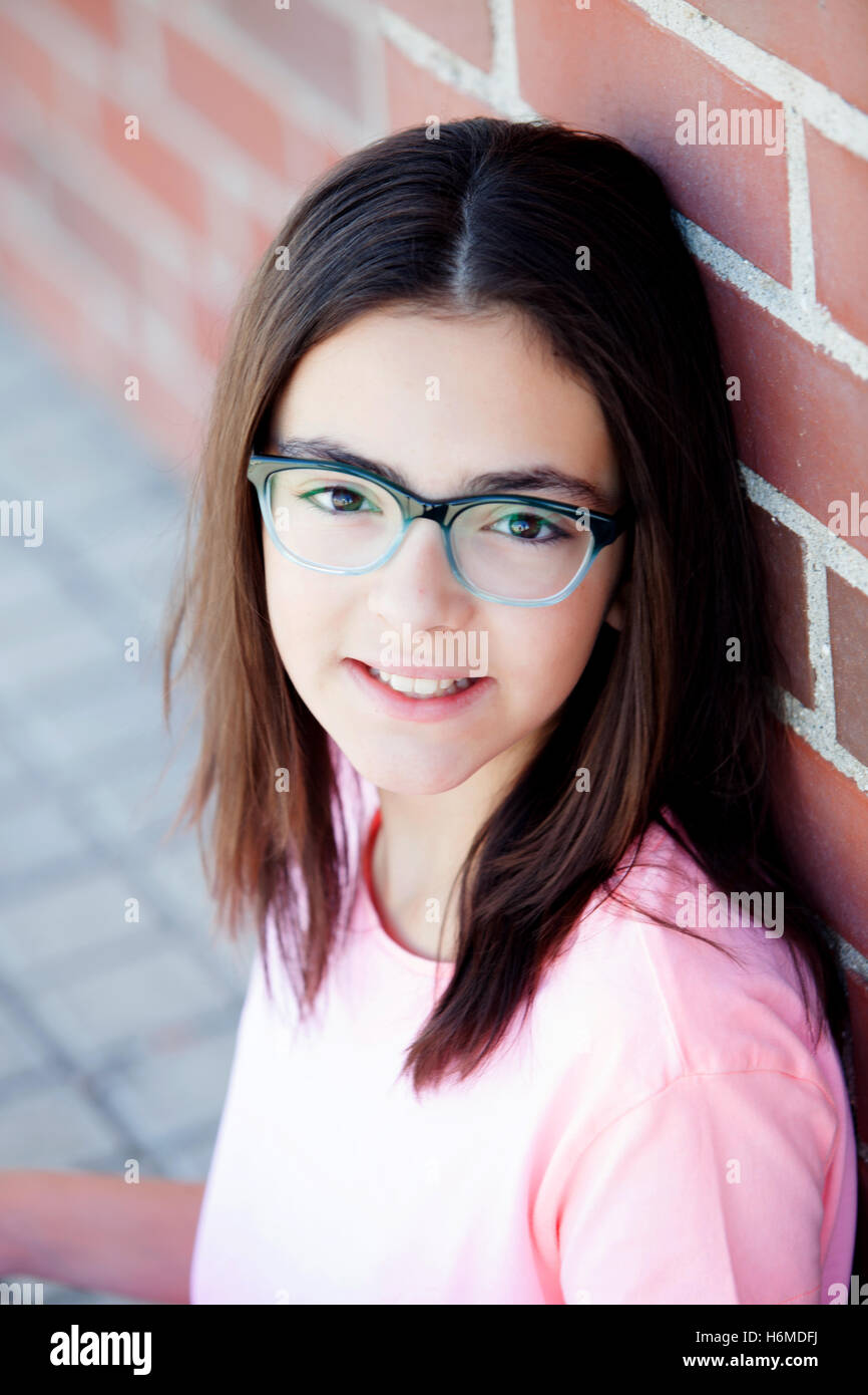 Preteenager girl next to a red brick wall with nice expression Stock Photo