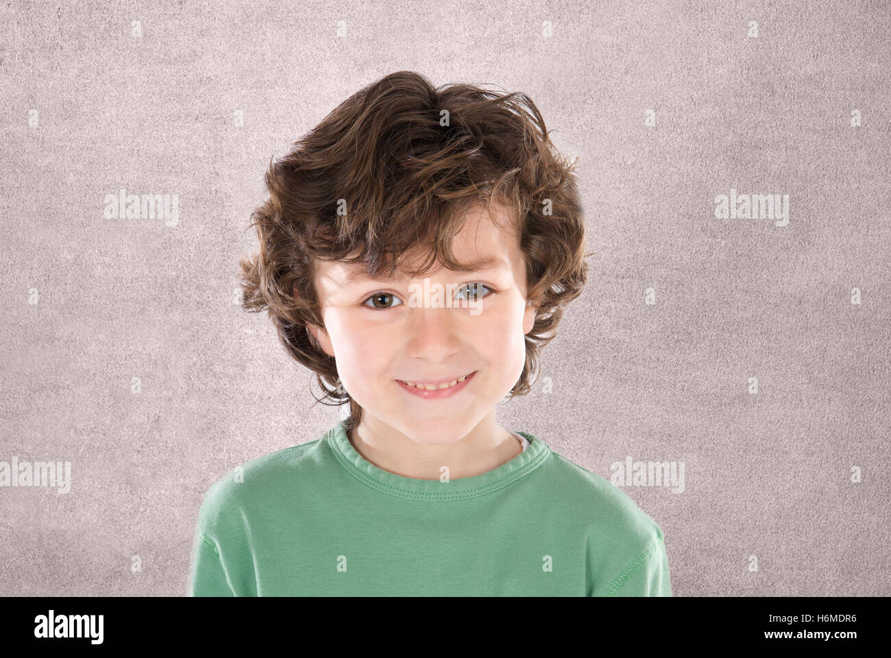 Smiling boy with six years old looking at camera on a grey background