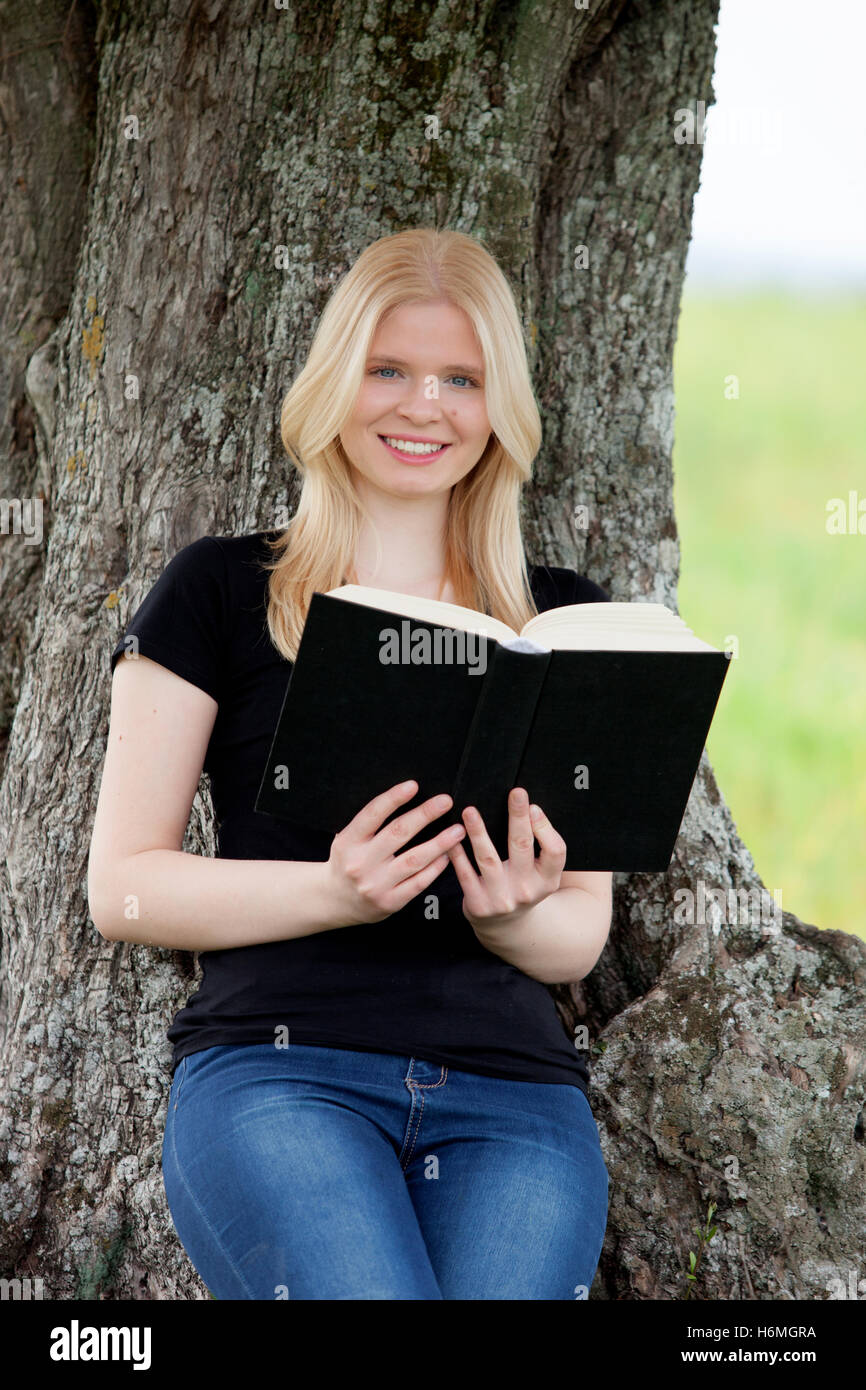 Relaxed young woman reading a book on nature Stock Photo - Alamy