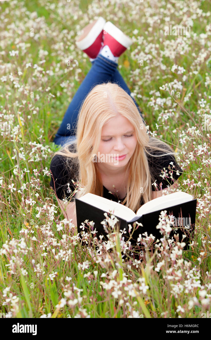 Relaxed young woman reading a book on nature Stock Photo - Alamy