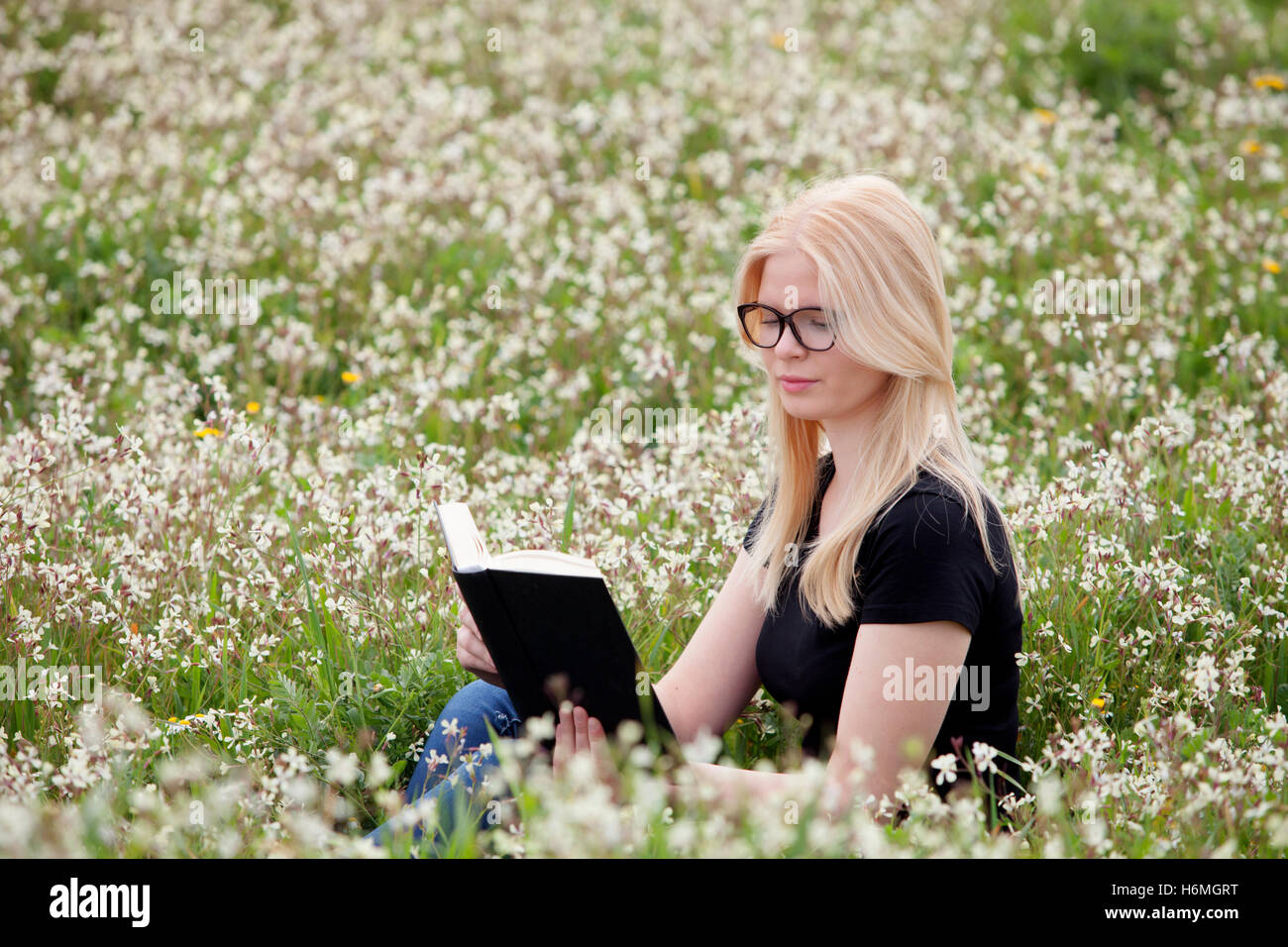 Relaxed young woman reading a book on nature Stock Photo - Alamy