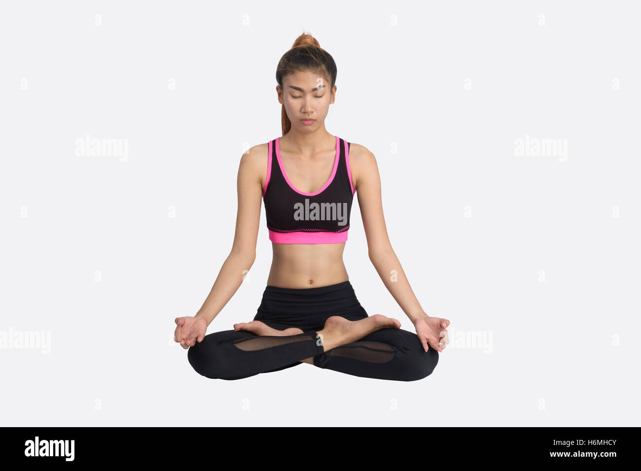Asian woman practicing yoga in the lotus position on isolated white background. Stock Photo