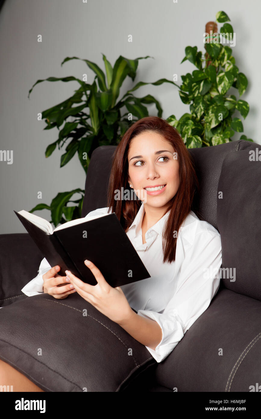 Young girl reading a book on the sofa at home Stock Photo - Alamy