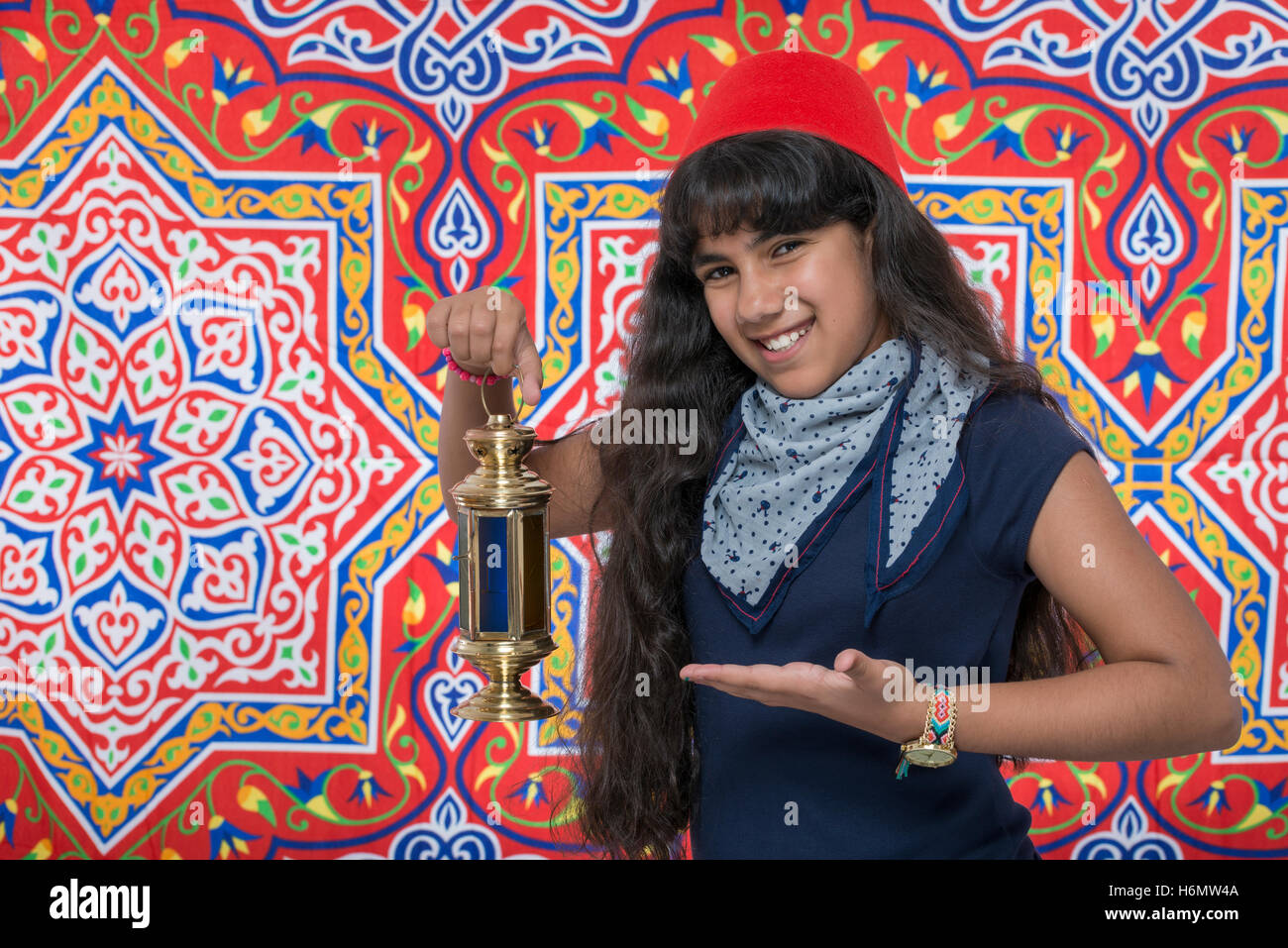 Happy Smiling Girl with Lantern Celebrating Ramadan over Ramadan Fabric Stock Photo