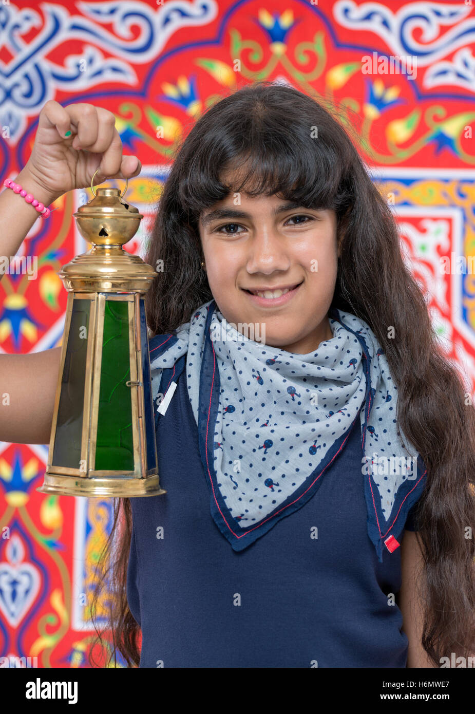 Happy Young Girl with Lantern Celebrating Ramadan over Ramadan Fabric Stock Photo