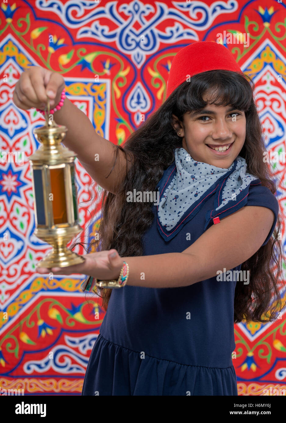 Happy Young Girl Holding Ramadan Lantern over Ramadan Fabric Stock Photo