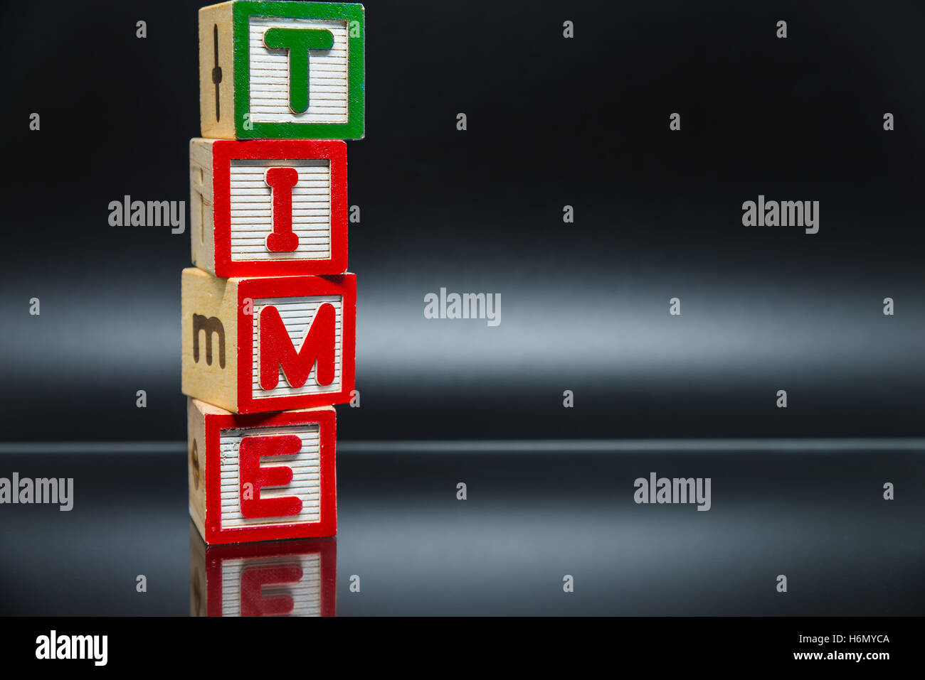 TIME word wooden block arrange in vertical style on black background ...