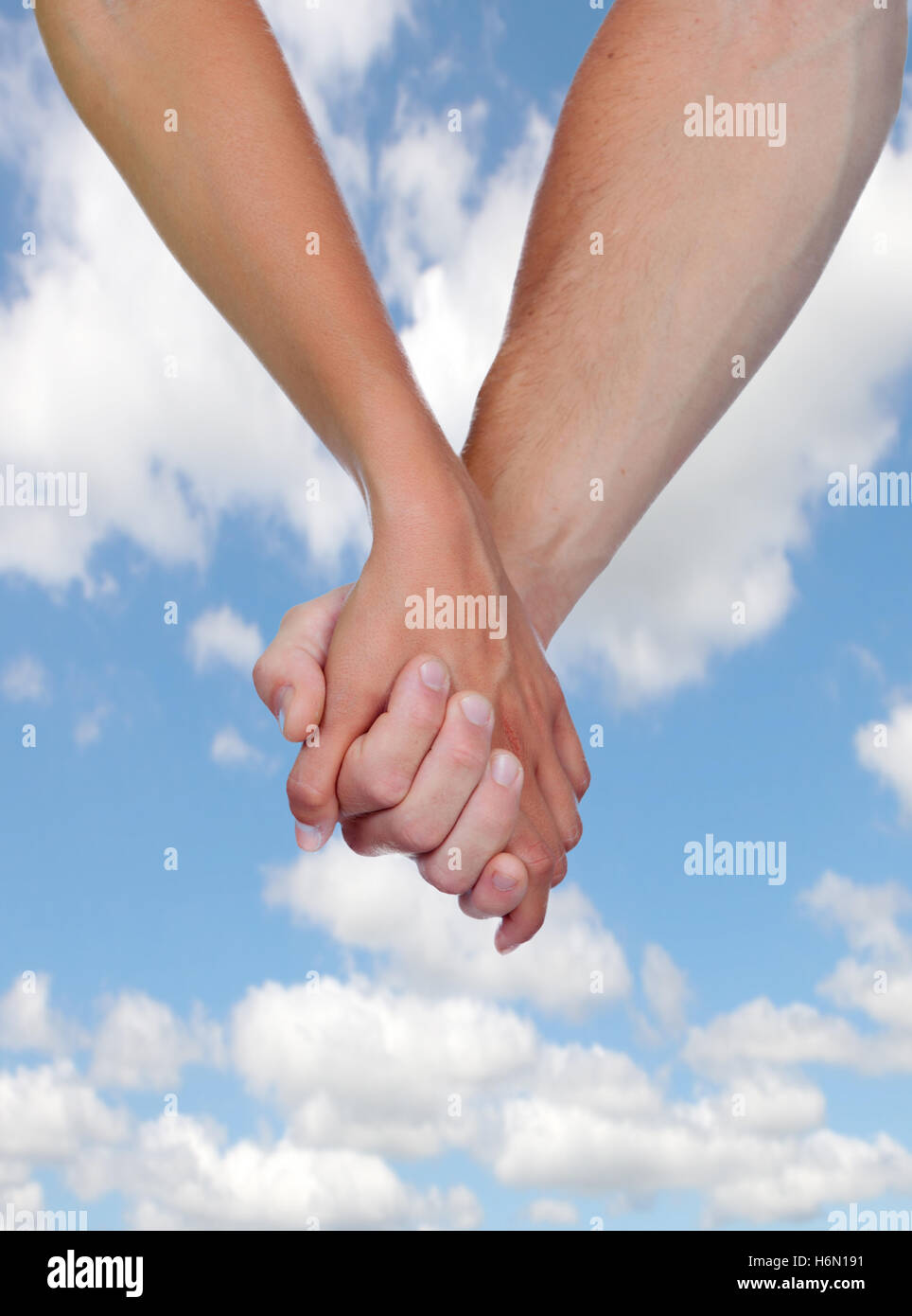 Two hands clasped in love with a blue sky background Stock Photo