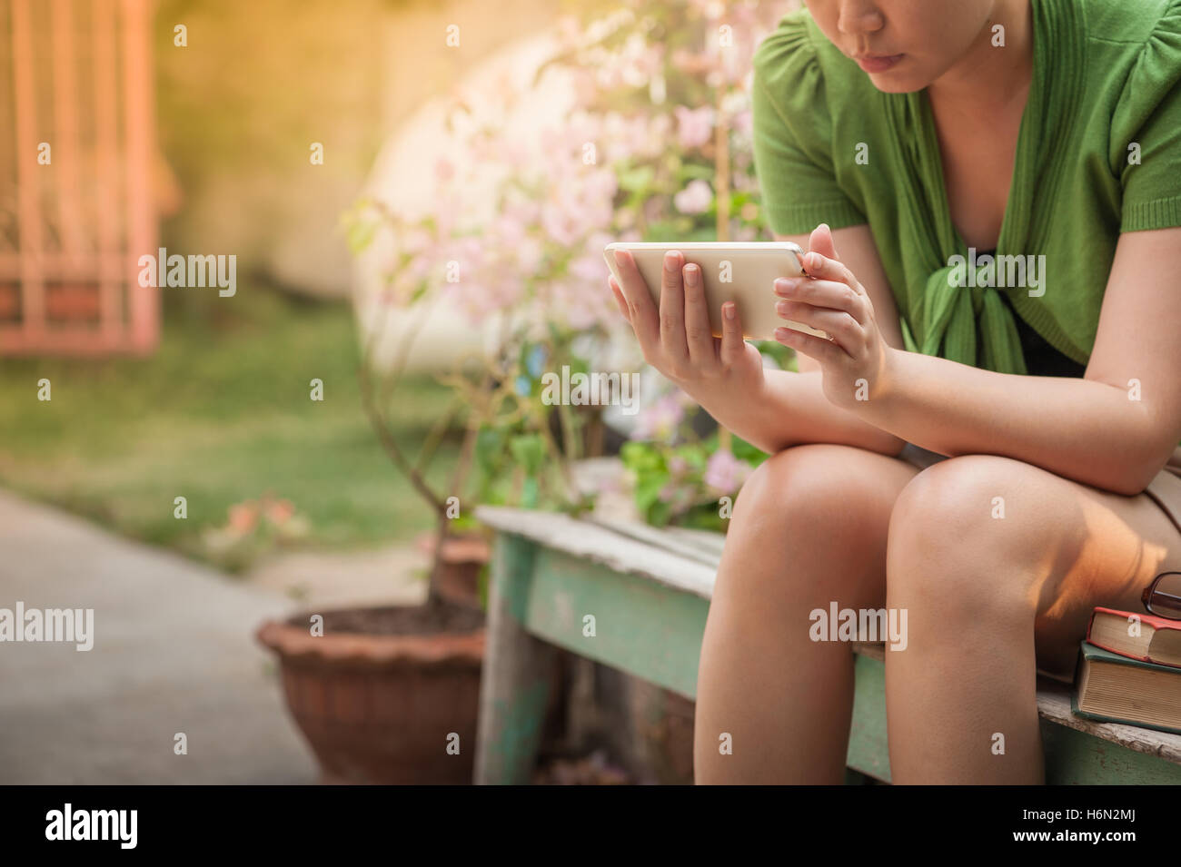 Morning lifestyle scene of young hipster woman using mobile phone while sitting on wood bench. trendy lifestyle with digital tec Stock Photo