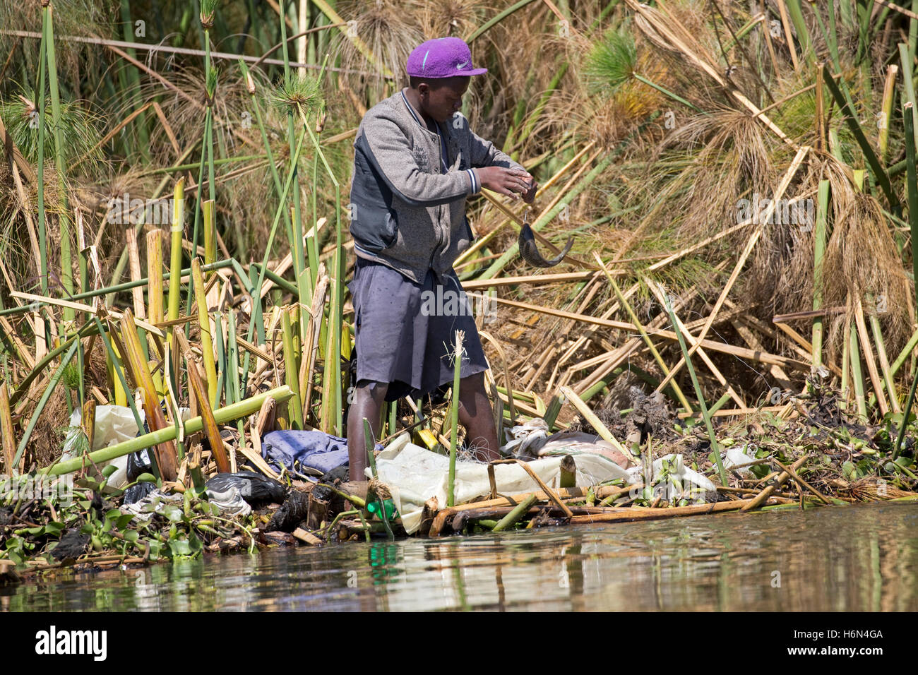 African fisherman catches fish using handline from papyrus at edge of Lake Naivasha Kenya Stock Photo