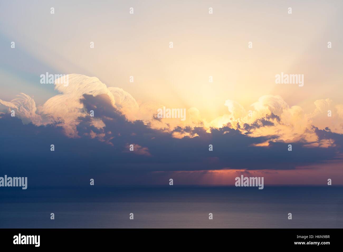 Blue sky with clouds, sea and sun on the horizon Stock Photo - Alamy