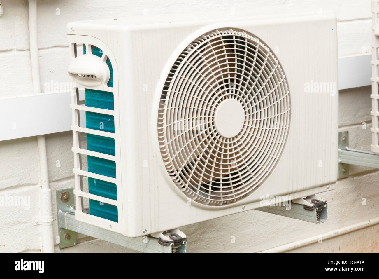 Single weathered white air conditioning unit mounted on exterior home wall Stock Photo