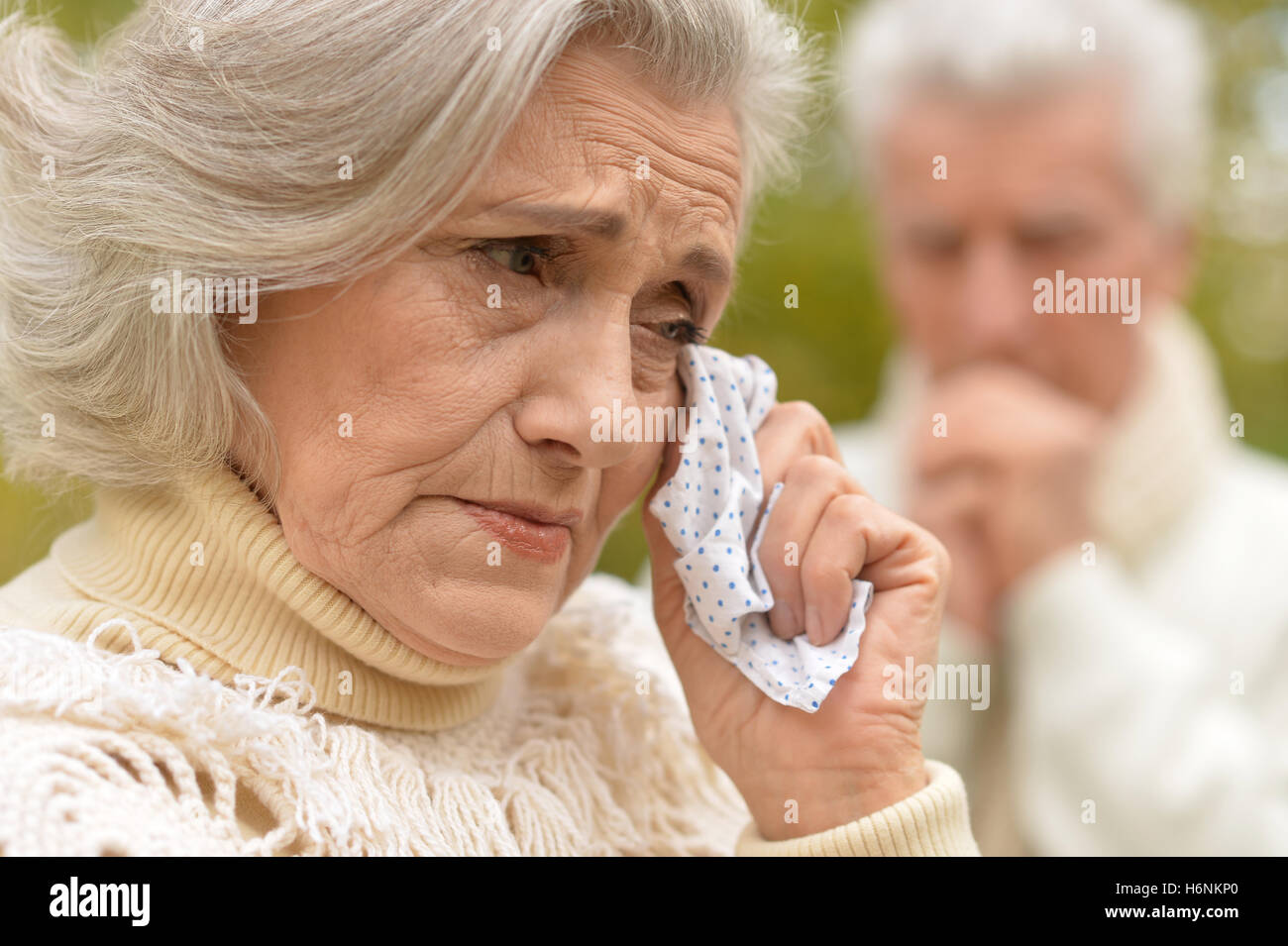 Sad aged woman crying next to an elderly man Stock Photo