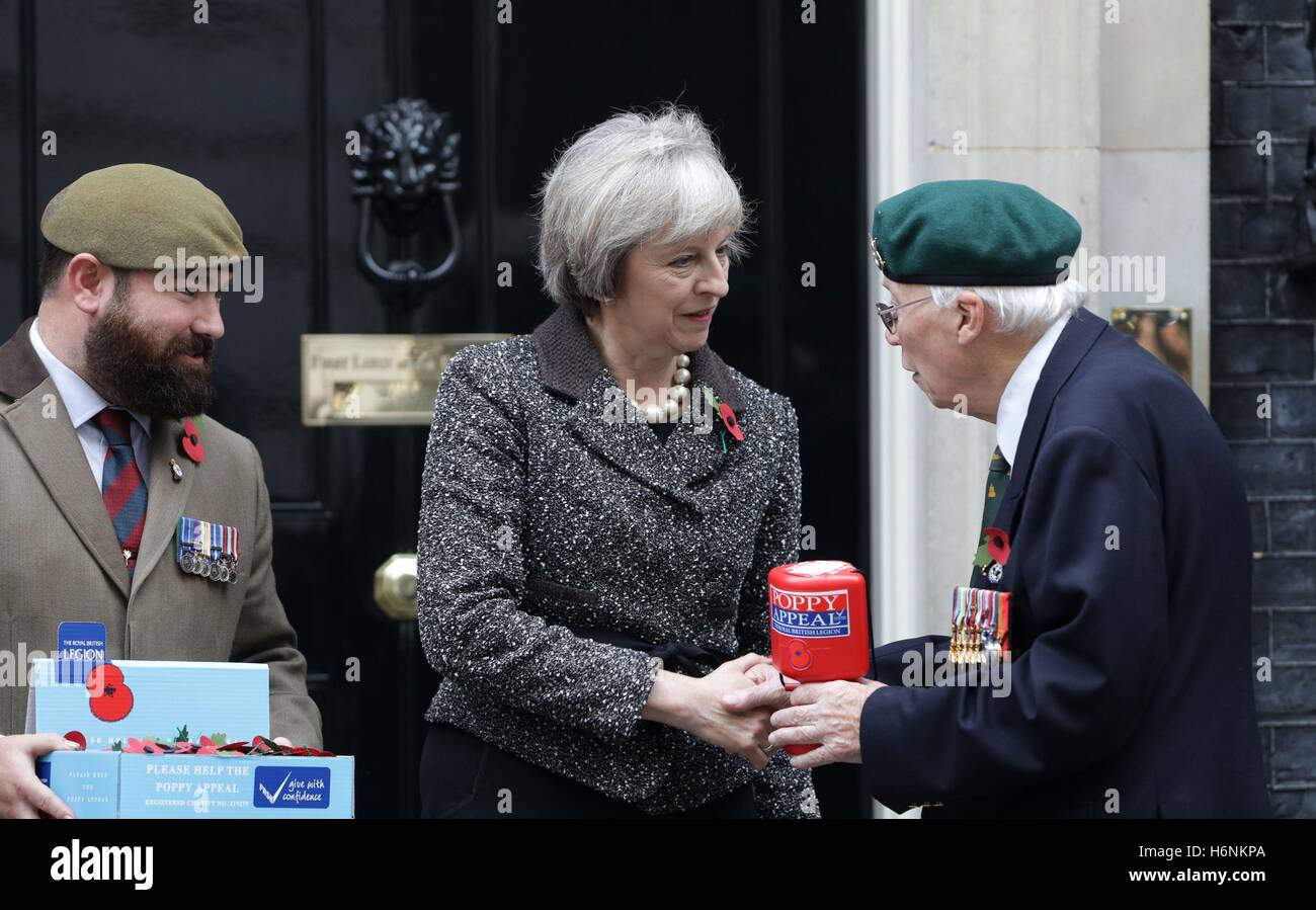 Prime Minister Theresa May meets veterans Stewart Harris (left), 32, and Roy Miller (right), 92, who are involved with the Royal British Legion's Poppy Appeal, as she makes her donation and receives her Poppy outside 10 Downing Street, London. Stock Photo