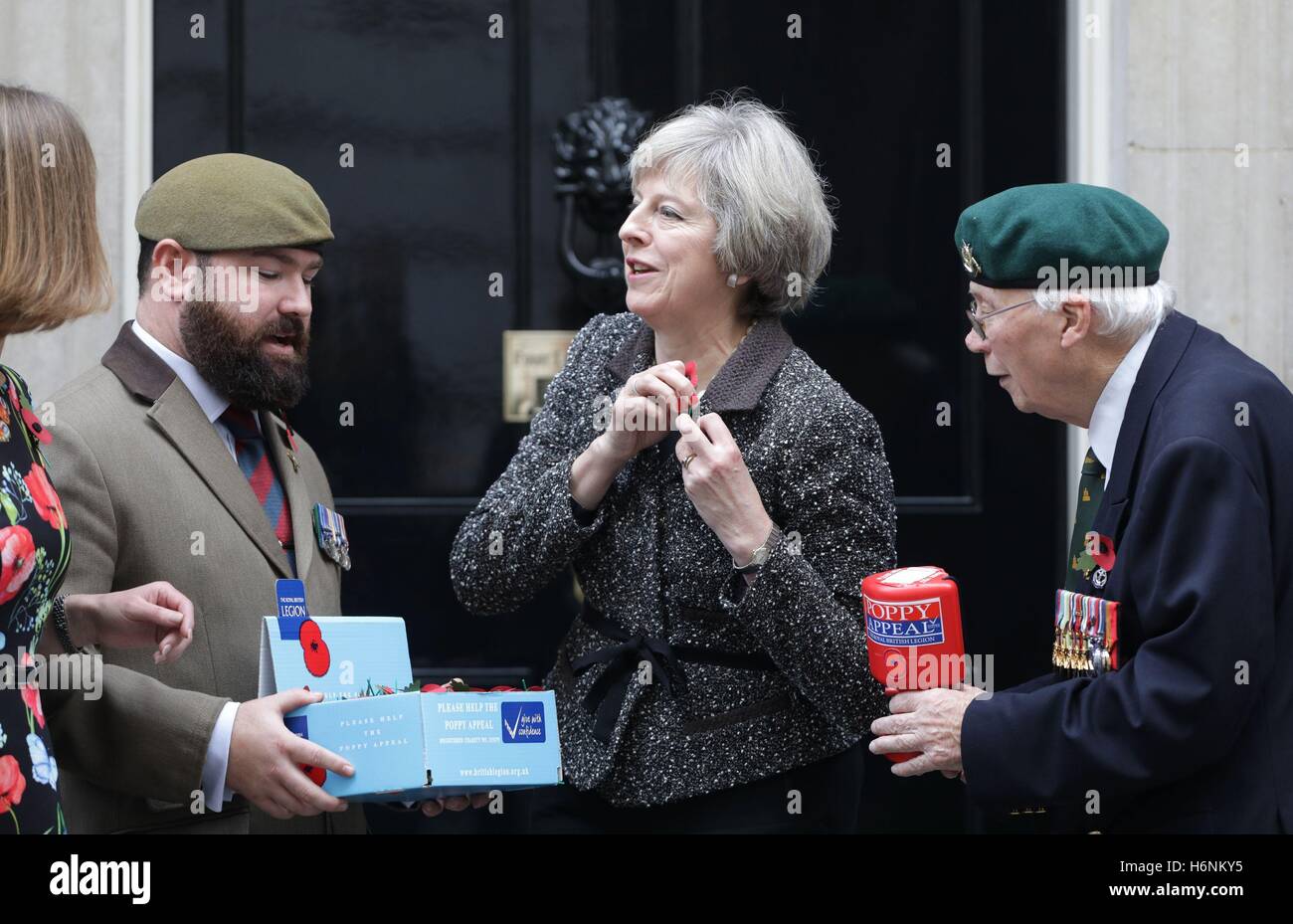 Prime Minister Theresa May meets veterans Stewart Harris (left), 32, and Roy Miller (right), 92, who are involved with the Royal British Legion's Poppy Appeal, as she makes her donation and receives her Poppy outside 10 Downing Street, London. Stock Photo
