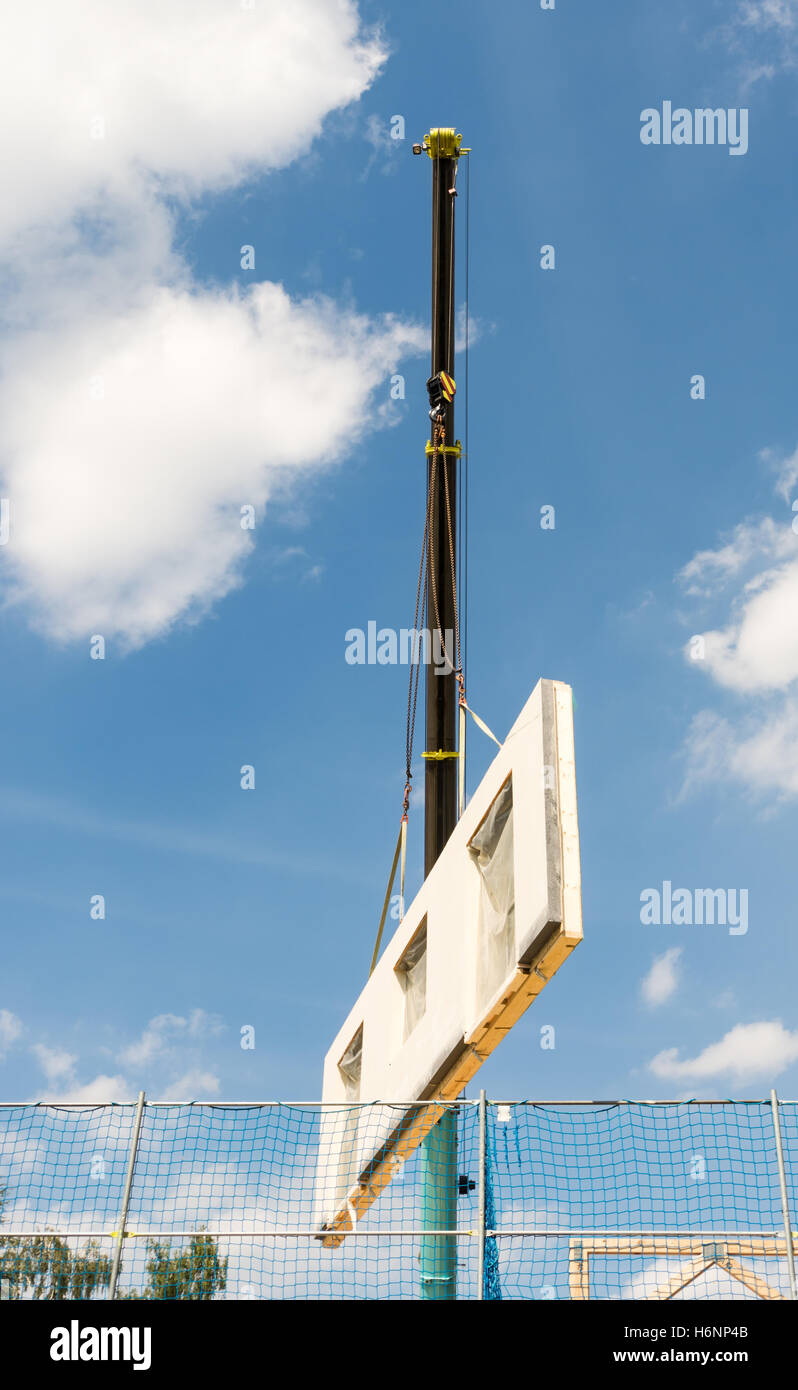 Assembling a prefabricated house - wall is hanging on a crane Stock Photo