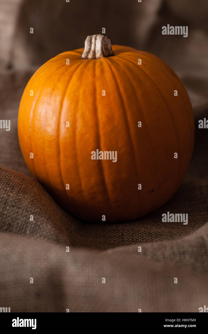 Whole pumpkin sat on a burlap sack ready for Halloween Stock Photo - Alamy