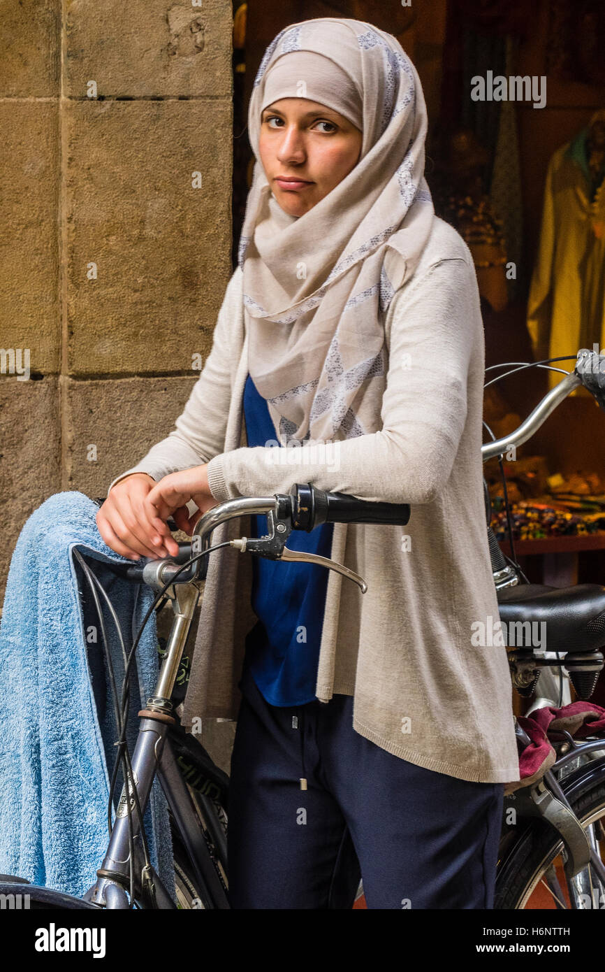 Muslim 20 something female wearing a hijab and standing by her bicycle in the streets of Barcelona, Spain. Stock Photo