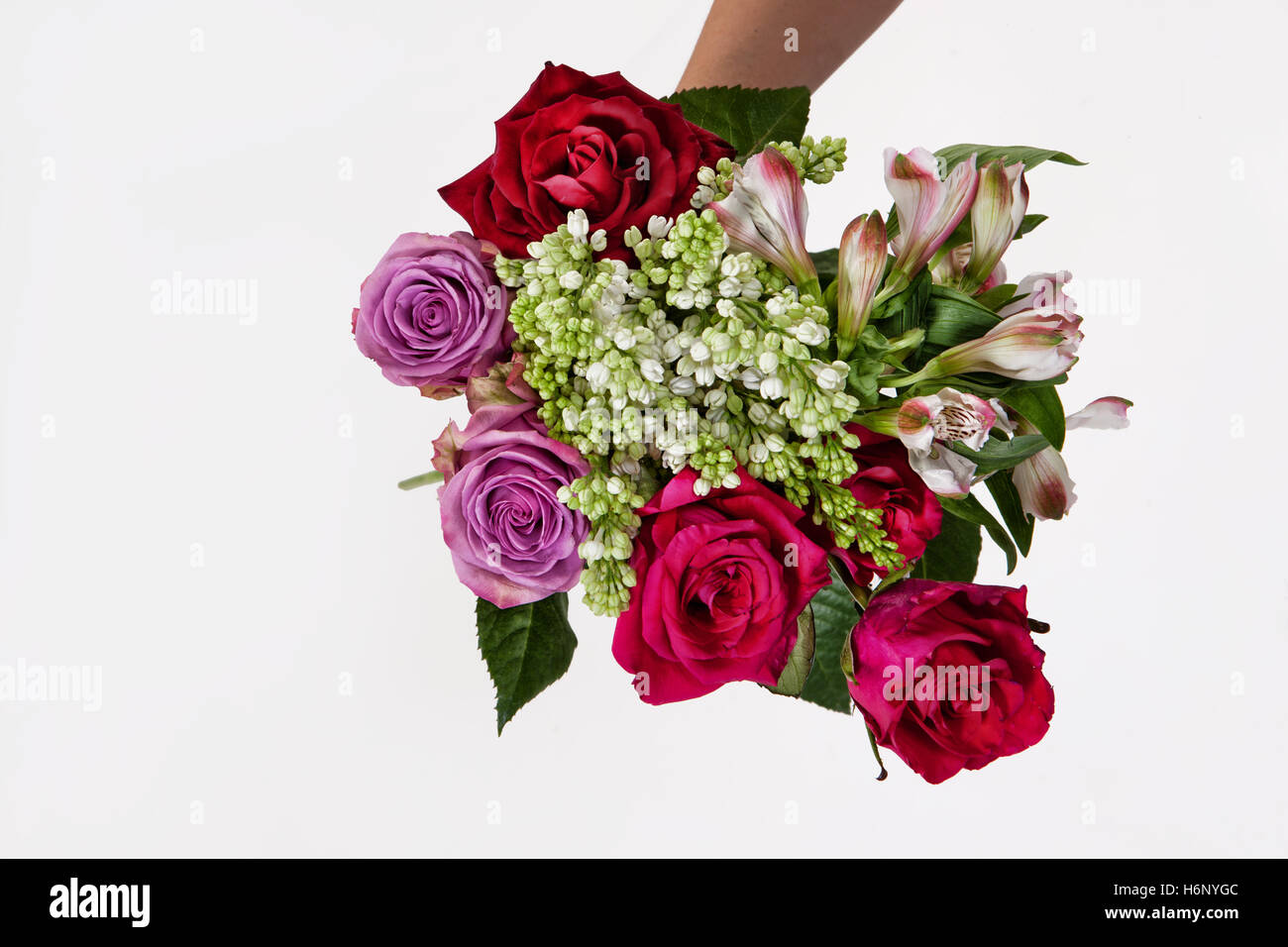 Hand holding a bouquet of different flowers on an isolated studio