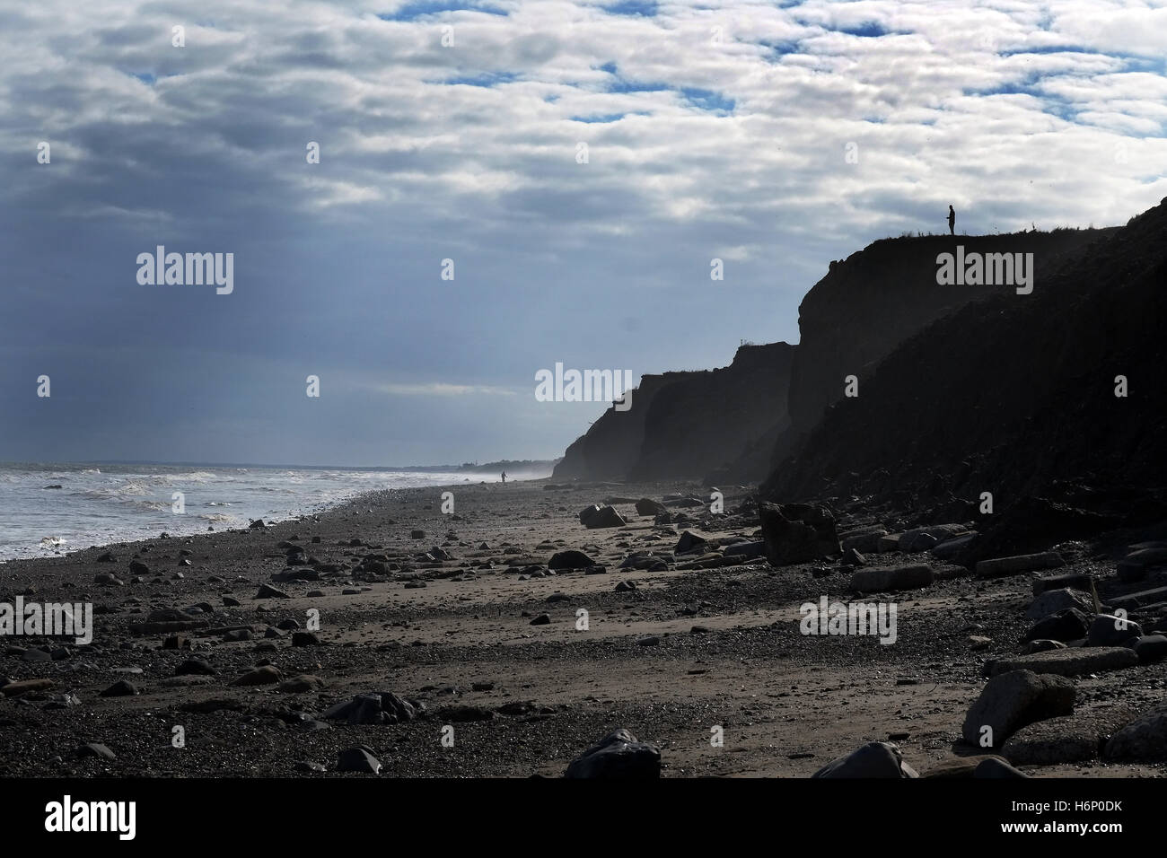 Figure on cliff top on fast eroding clay cliffs at Skipsea, Yorkshire, UK. Stock Photo