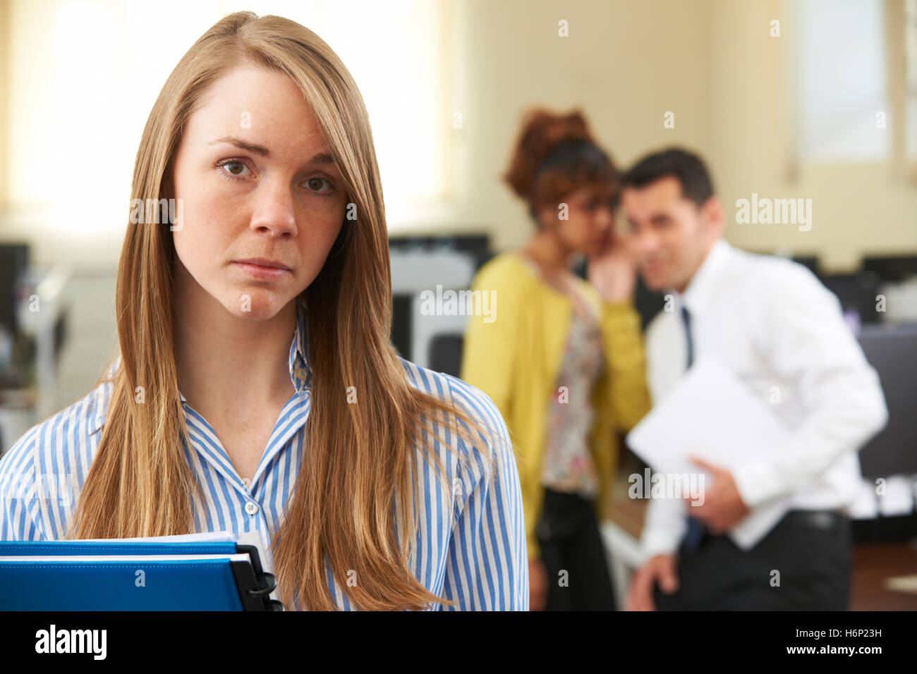 Businesswoman Being Gossiped About By Colleagues In Office Stock Photo