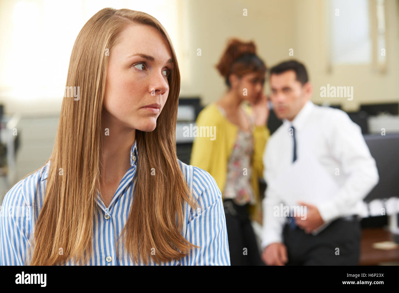 Businesswoman Being Gossiped About By Colleagues In Office Stock Photo