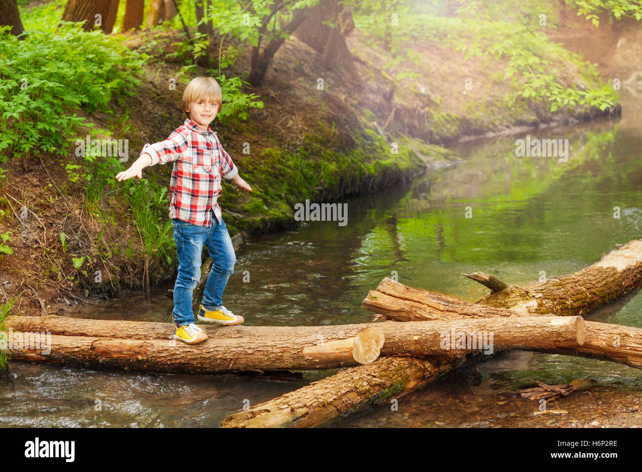 Happy boy crossing a river in the forest Stock Photo