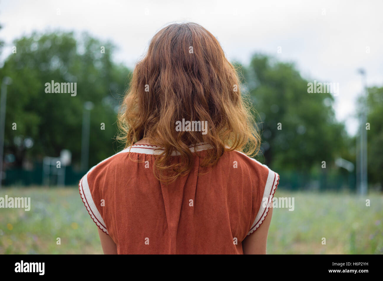 Rear view shot of a young woman standing in a park Stock Photo - Alamy