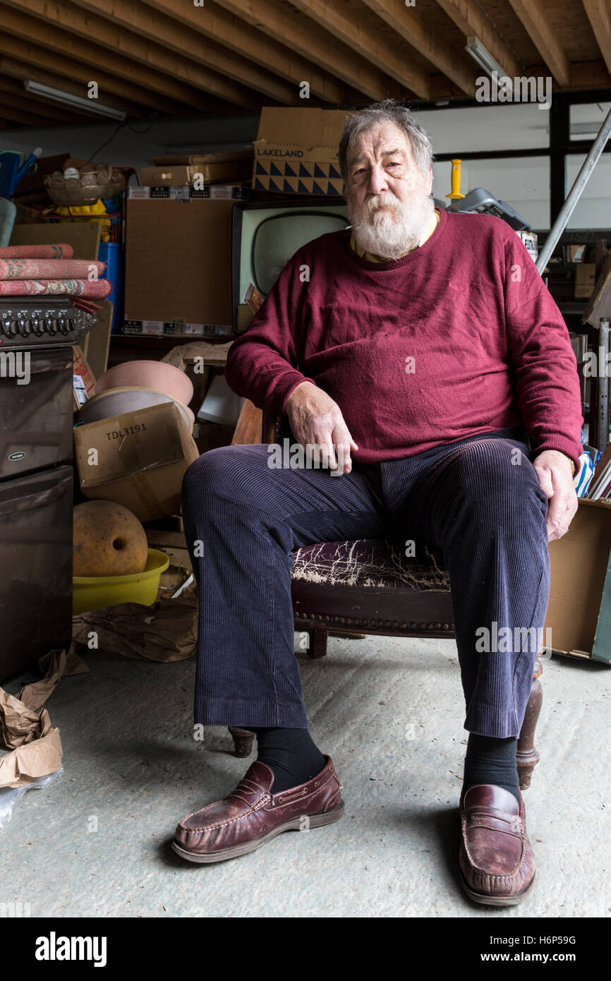 Older man sitting in an old chair in his junk shop. Cahersiveen, County Kerry, Ireland. Stock Photo