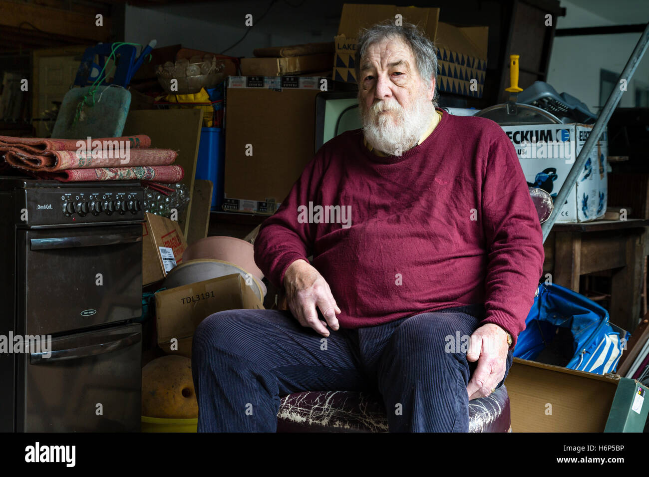 Older man sitting in an old chair in his junk shop. Cahersiveen, County Kerry, Ireland. Stock Photo