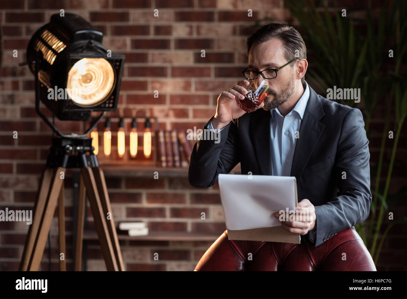 Serious stylish businessman taking a sip of whisky Stock Photo