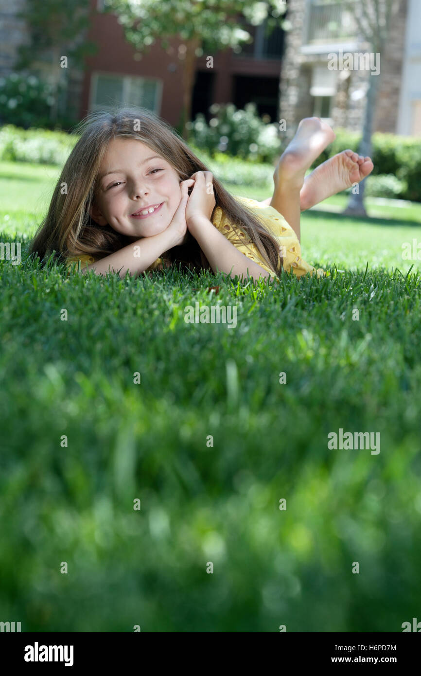 portrait of little girl laying on the grass in summer environment Stock ...