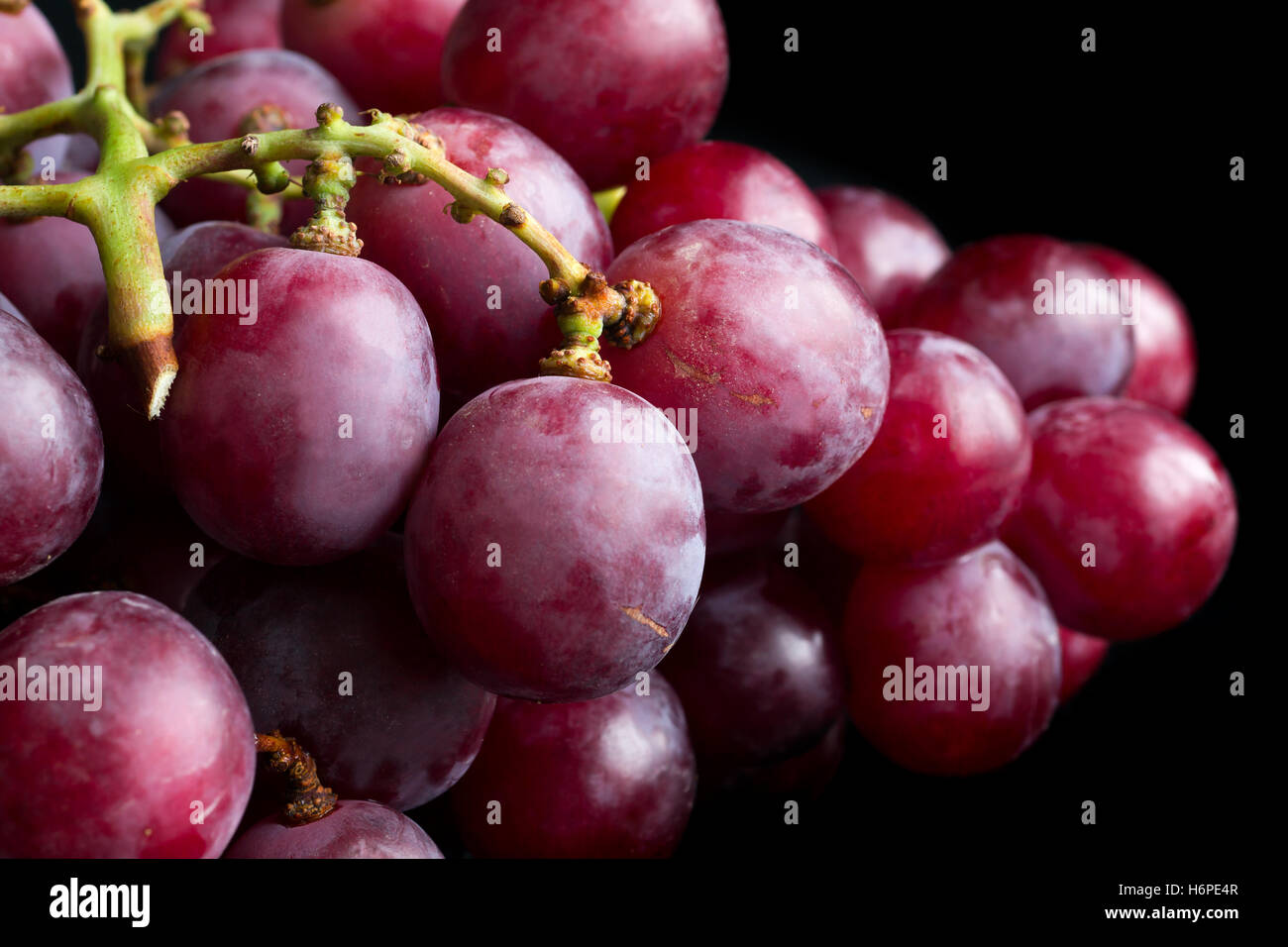 Bunch of red grapes on black surface. Stock Photo