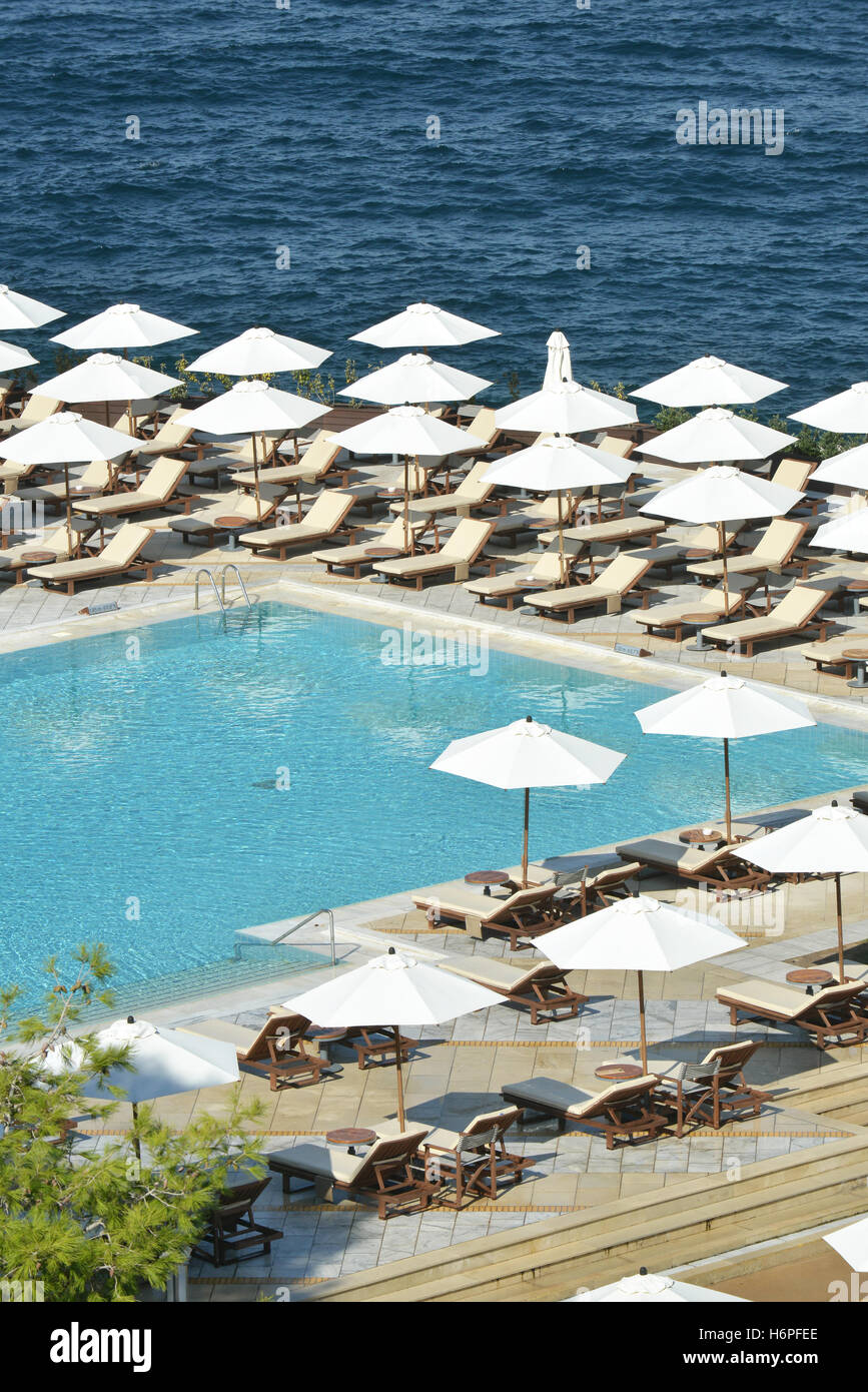 sun loungers and umbrellas around a hotel swimming pool Stock Photo