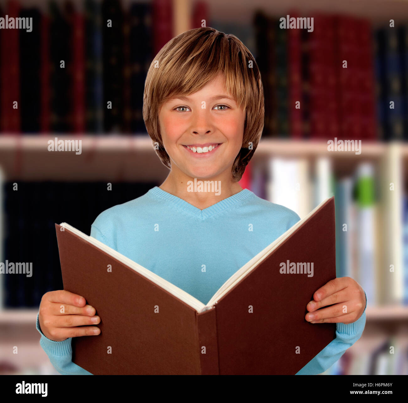 Preteen boy with a big book reading in the library Stock Photo - Alamy