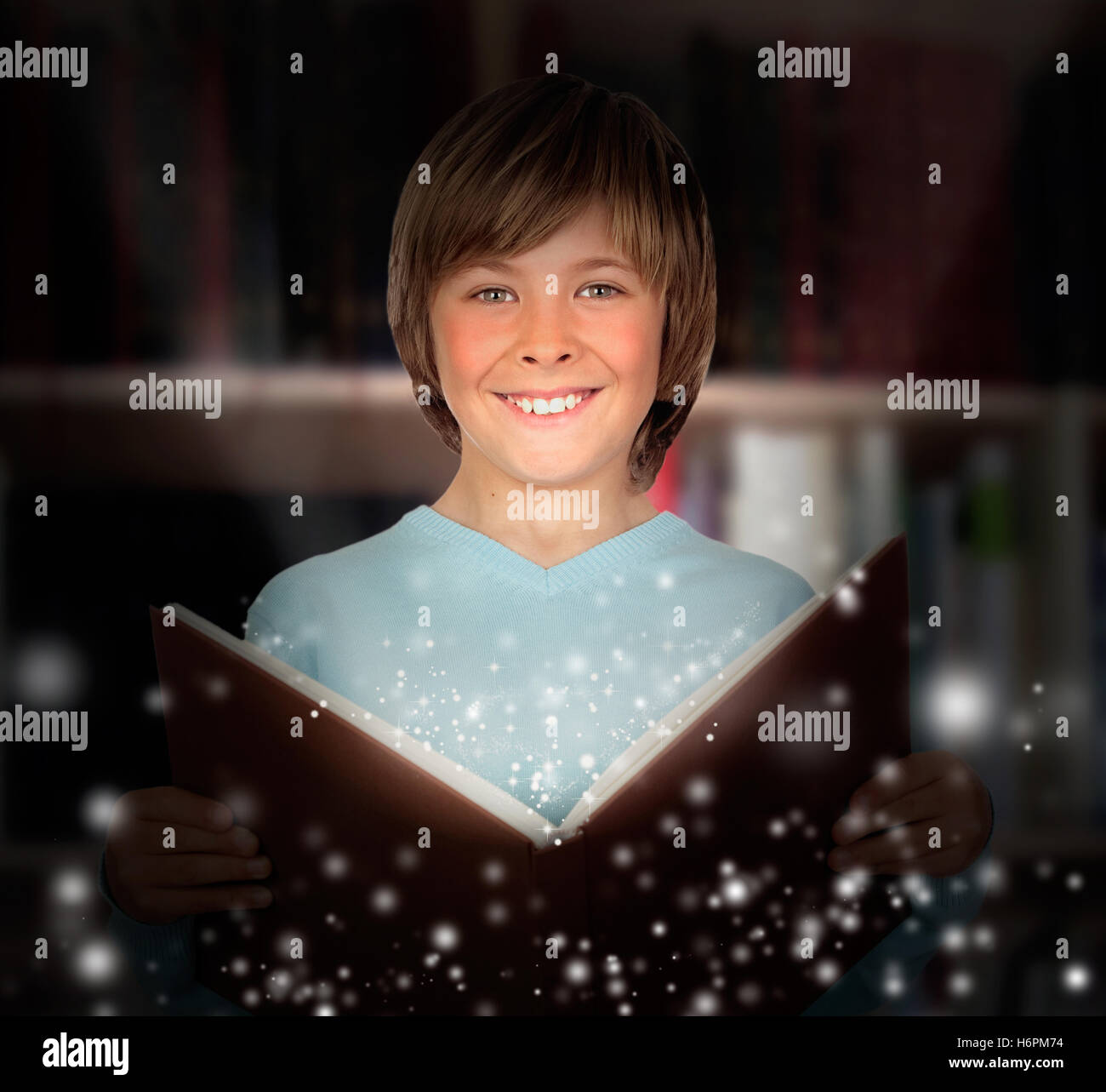 Preteen boy with a lighted book reading in the library Stock Photo - Alamy