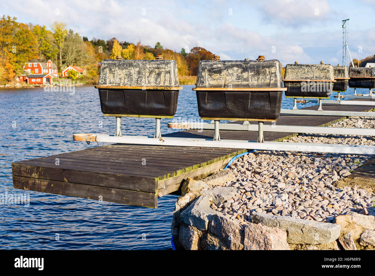 Floating mooring rigs on pier in autumn. Rectangular containers mounted on metal poles are used as floaters when in water. Stock Photo