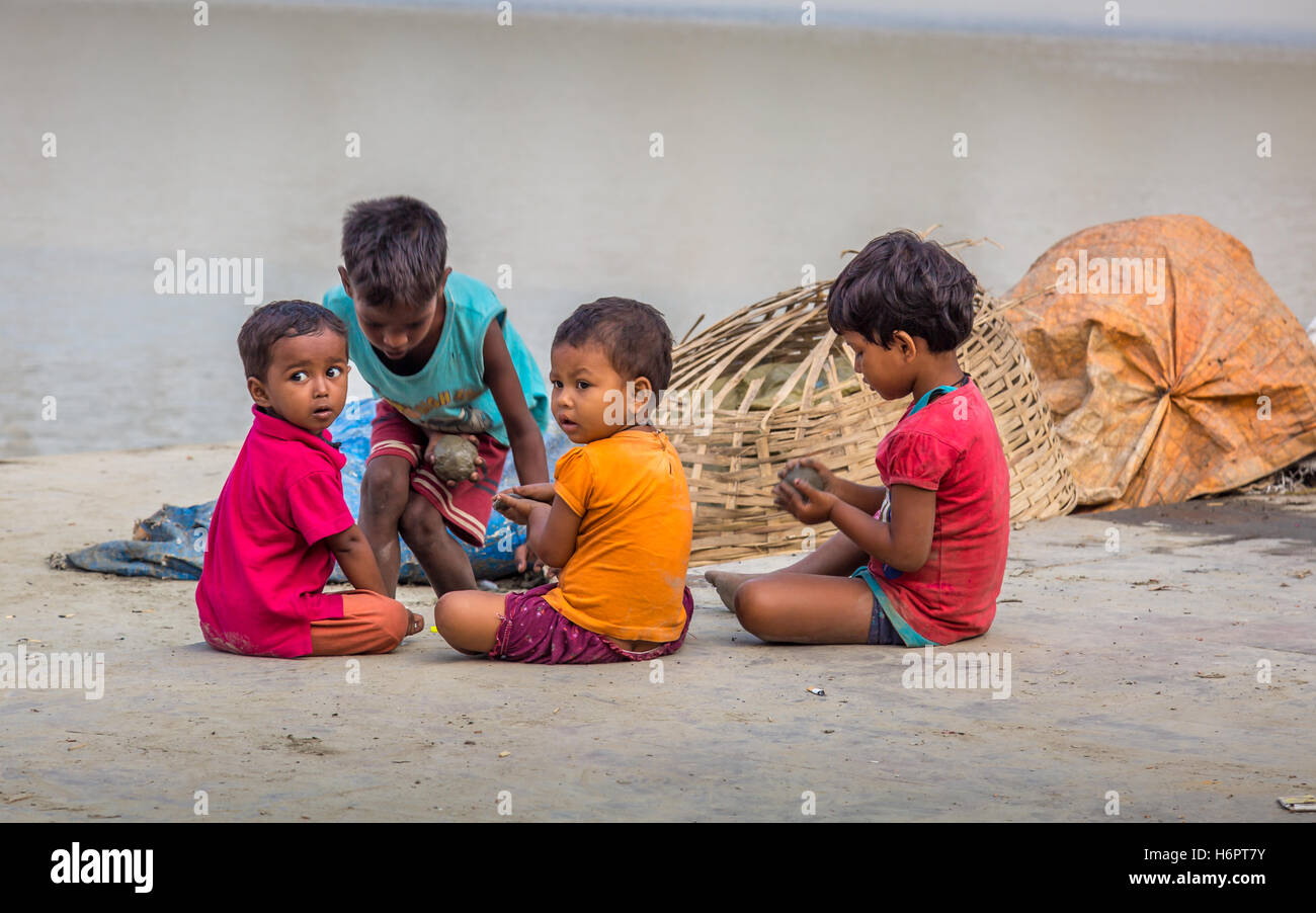 Street kids play with clay at Mallick Ghat, flower market, Kolkata, India. This ghat is located closest to the Howrah bridge. Stock Photo