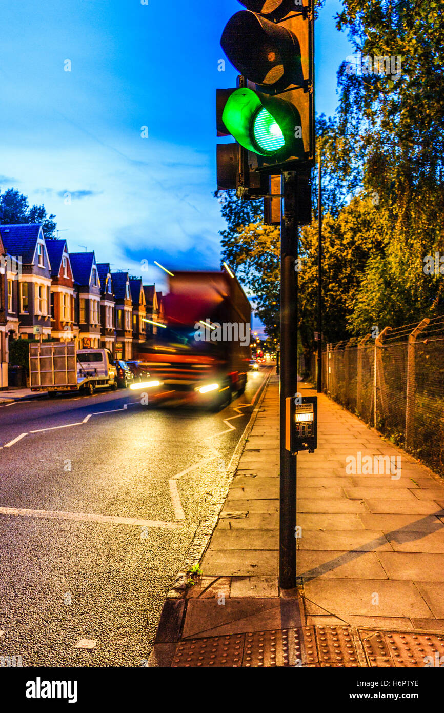 Blue and orange urban night scene with a motion-blurred lorry approaching a green traffic light in the foreground, Archway Road, London, UK Stock Photo