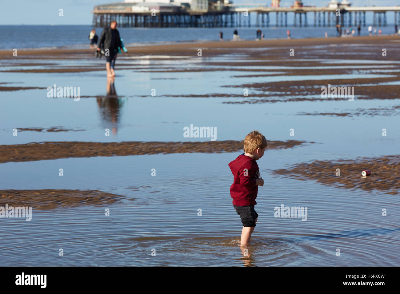 Blackpool child paddling beach puddles   Holiday sea side town resort Lancashire tourist attractions sea front attraction Touris Stock Photo