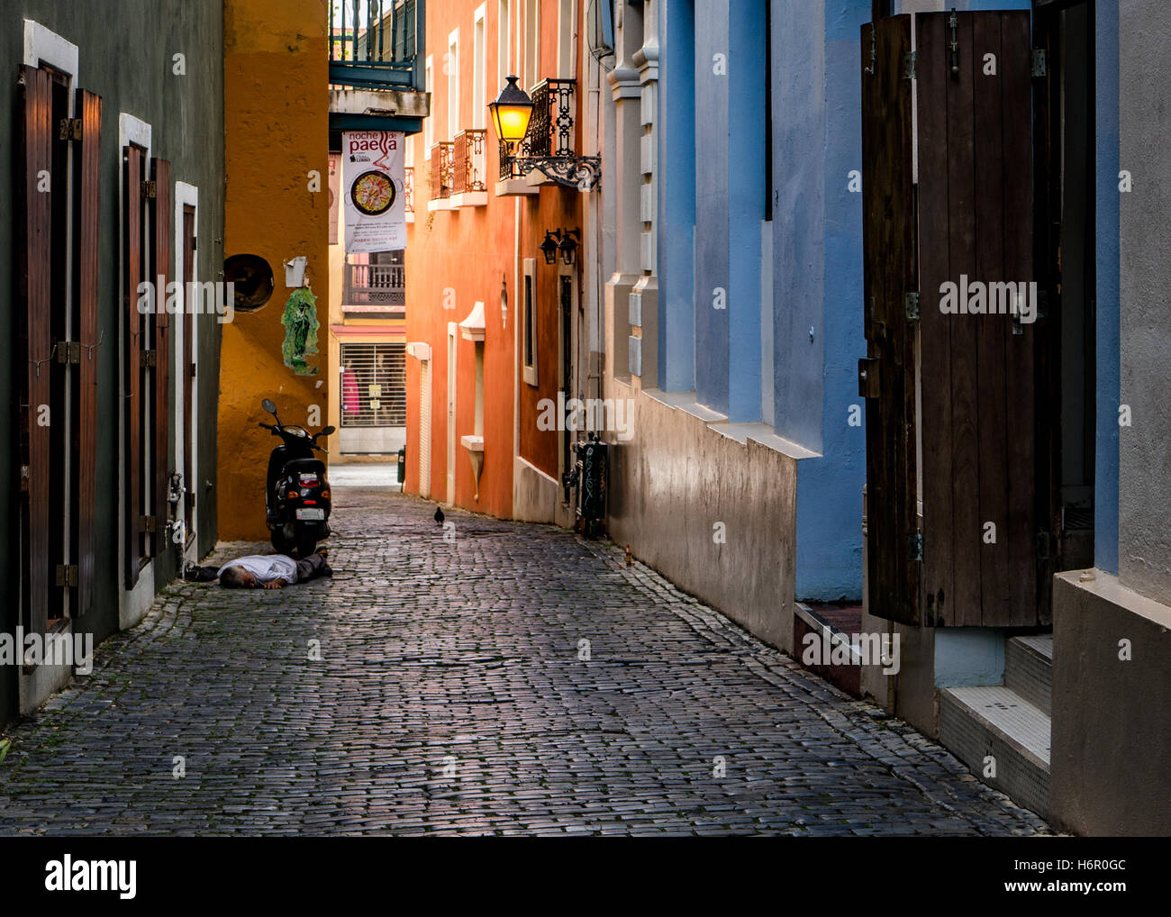 A man taking an afternoon siesta next to his scooter in an alley in Old San Juan (Puerto Rico) Stock Photo