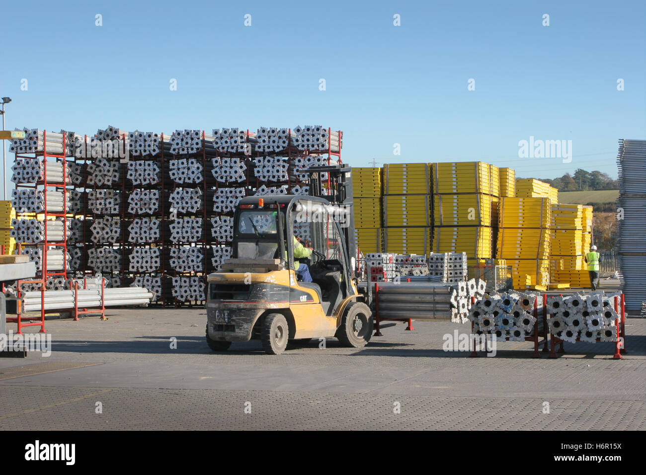 A forklift truck moves aluminium shoring products around a UK storage yard on a bright, sunny day. Stock Photo