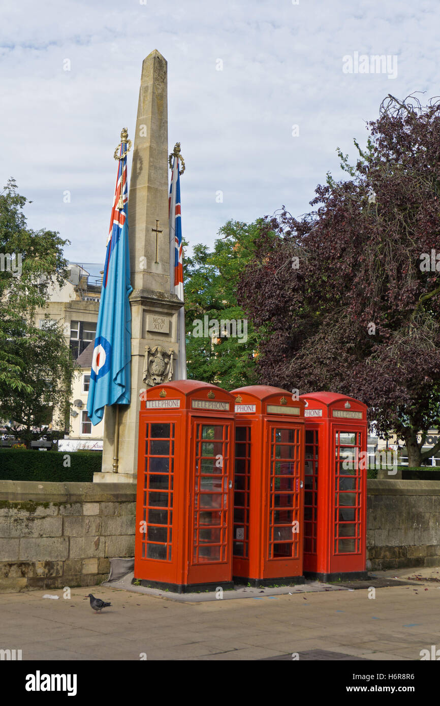 A trio of red telephone boxes with part of the Northampton War Memorial in the background; Northampton UK Stock Photo