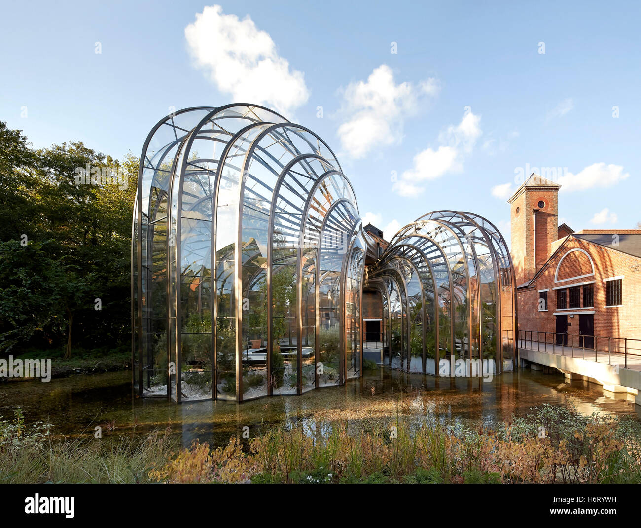 Historic mill site with curving greenhouse additions. Bombay Sapphire Distillery, Laverstoke, United Kingdom. Architect: Heatherwick, 2014. Stock Photo