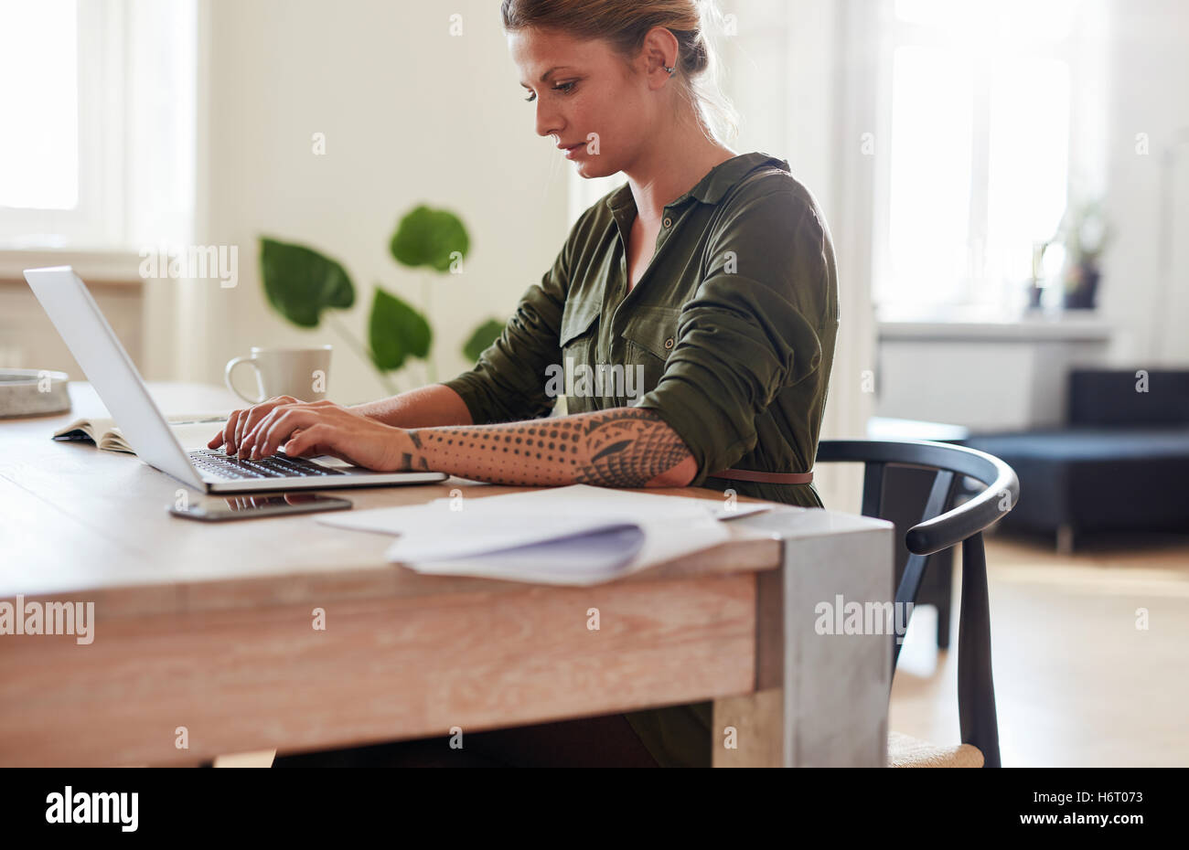 Shot of young woman sitting at table using laptop. Caucasian businesswoman working on laptop at home office. Stock Photo