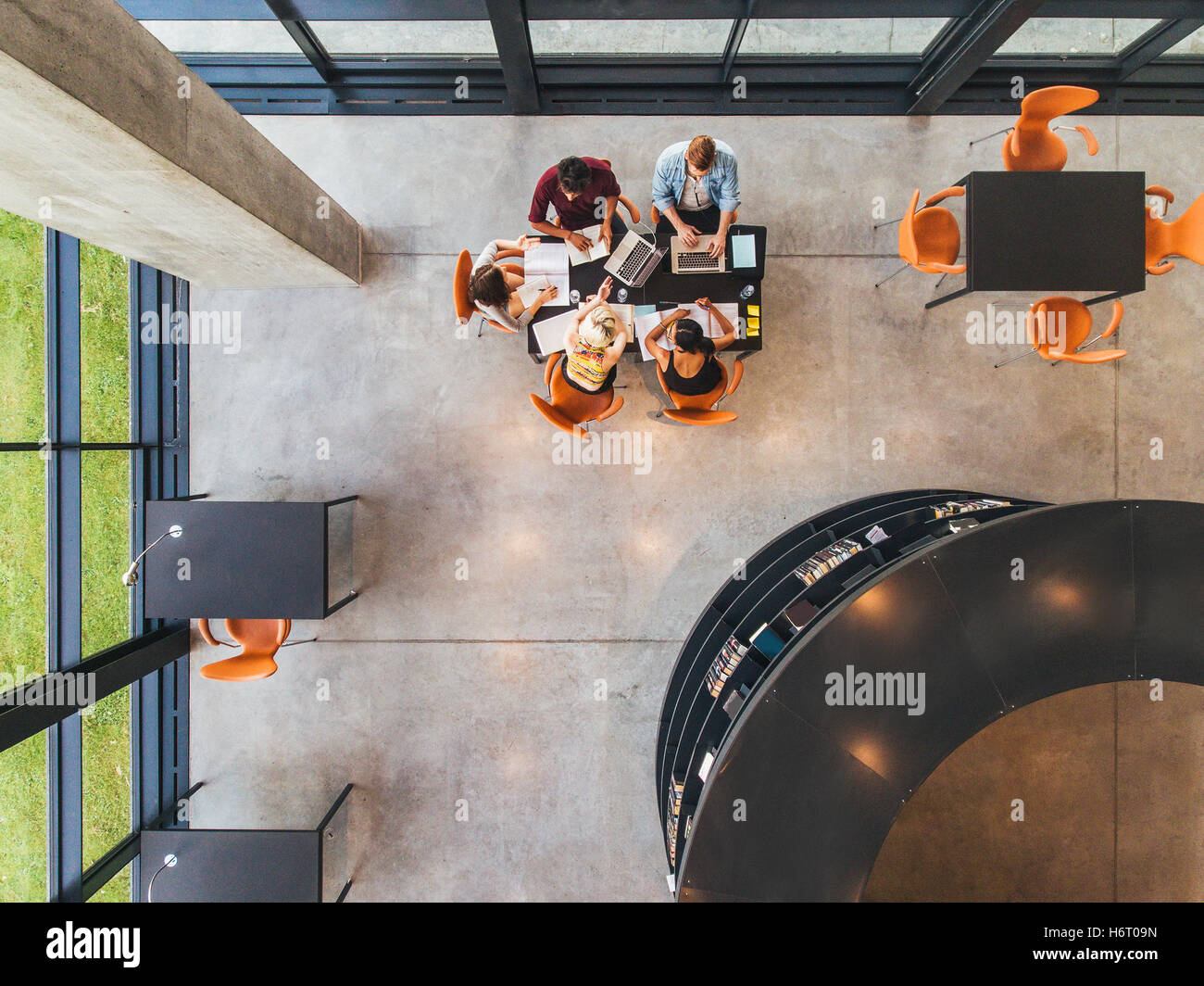 Top view of college students sitting in a library with books and laptop. Young people studying together at public library. Stock Photo
