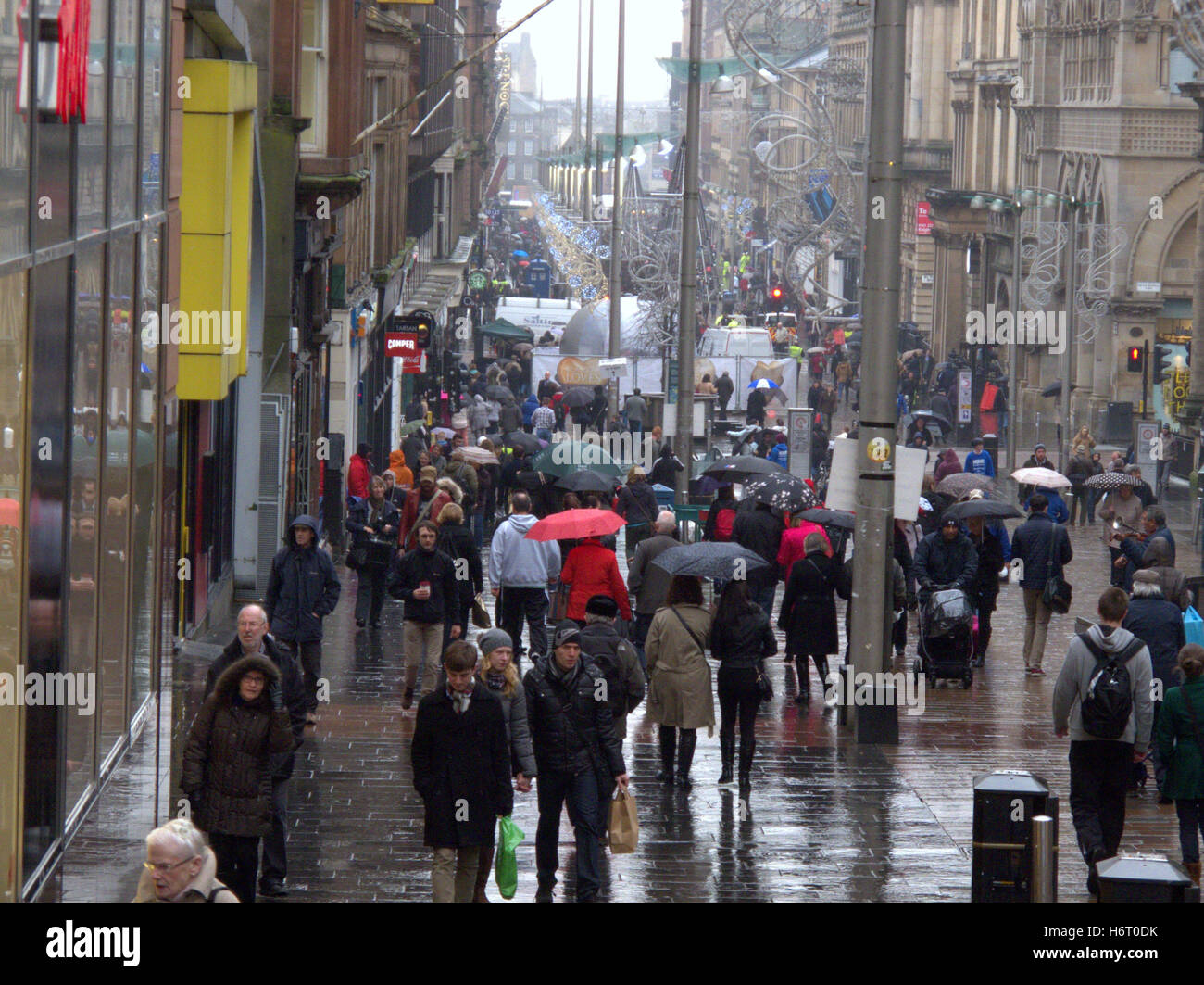 Glasgow in the rain wet streets and  red umbrella umbrellas shopping bags Stock Photo