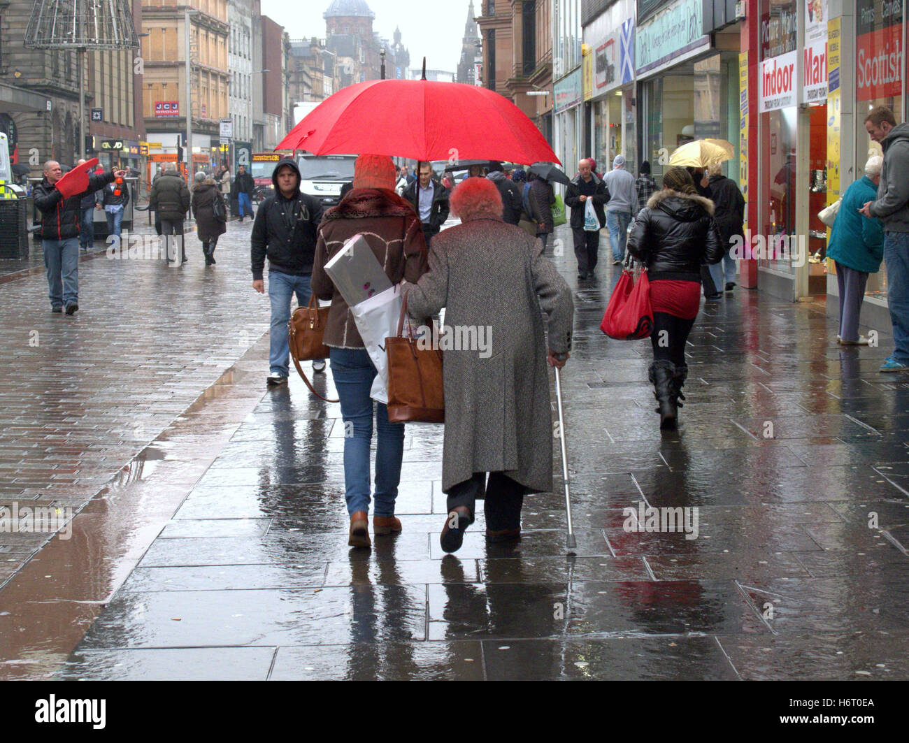 Glasgow in the rain wet streets and red  umbrella umbrellas shopping bags Stock Photo
