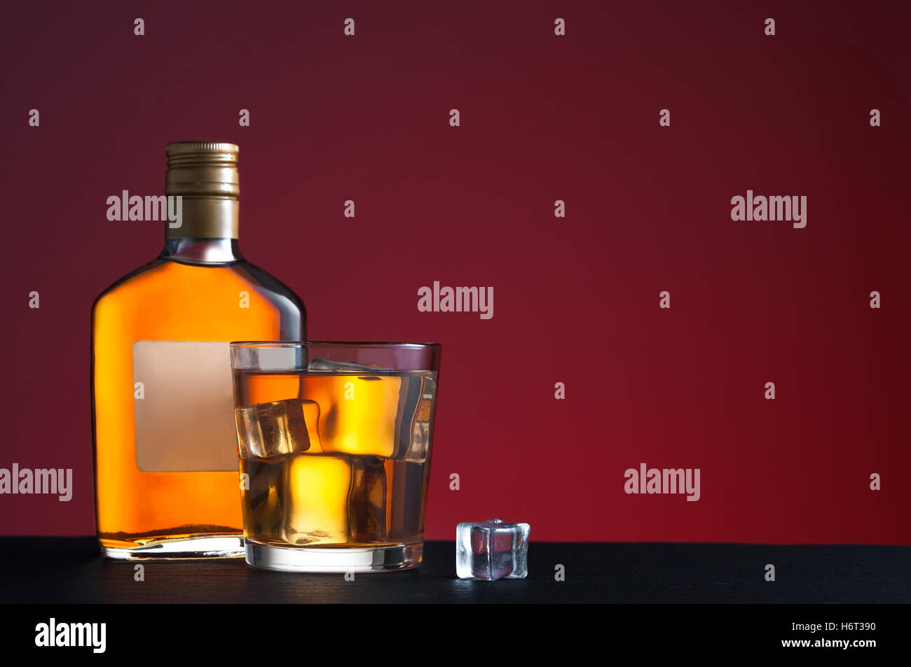 Whiskey on the rocks and glass bottle in red background Stock Photo - Alamy