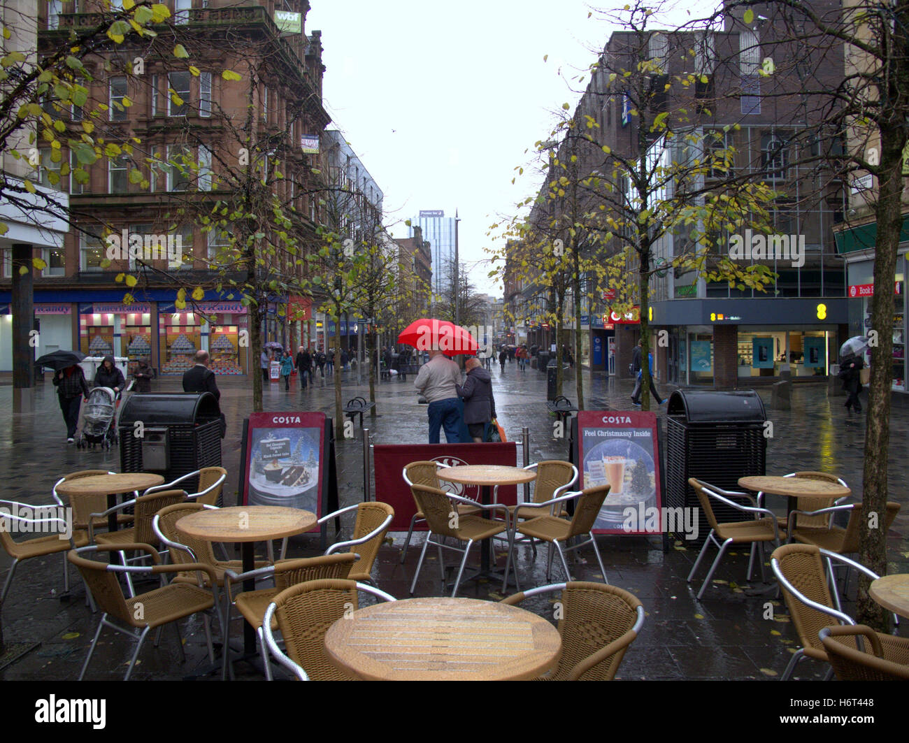 Glasgow in the rain wet streets and umbrella umbrellas shopping bags Stock Photo